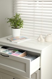 Photo of Chest of drawers with different folded clothes indoors