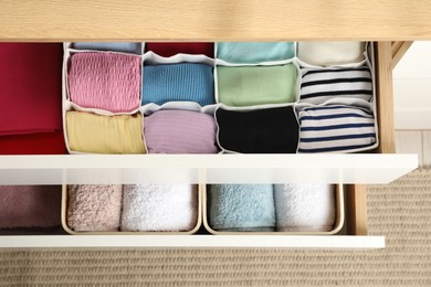 Chest of drawers with different folded clothes indoors, top view