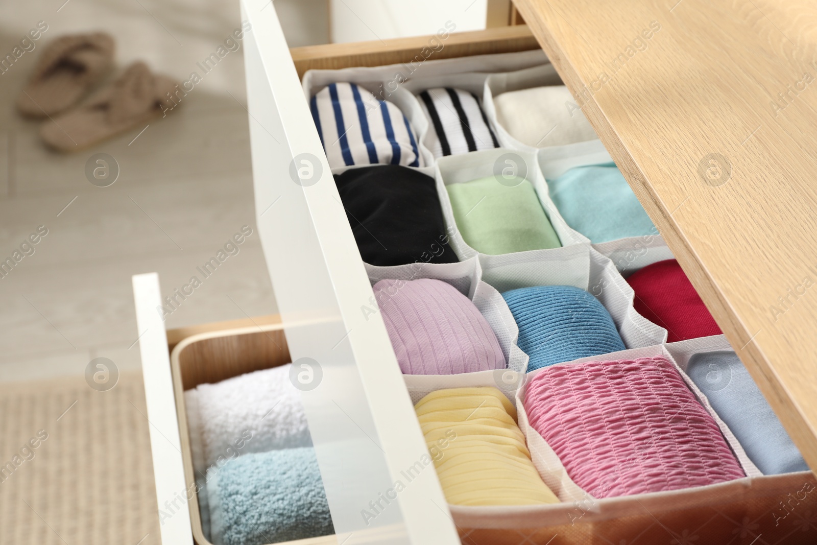 Photo of Chest of drawers with different folded clothes indoors, closeup