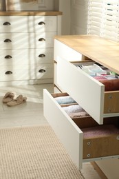 Chest of drawers with different folded clothes indoors