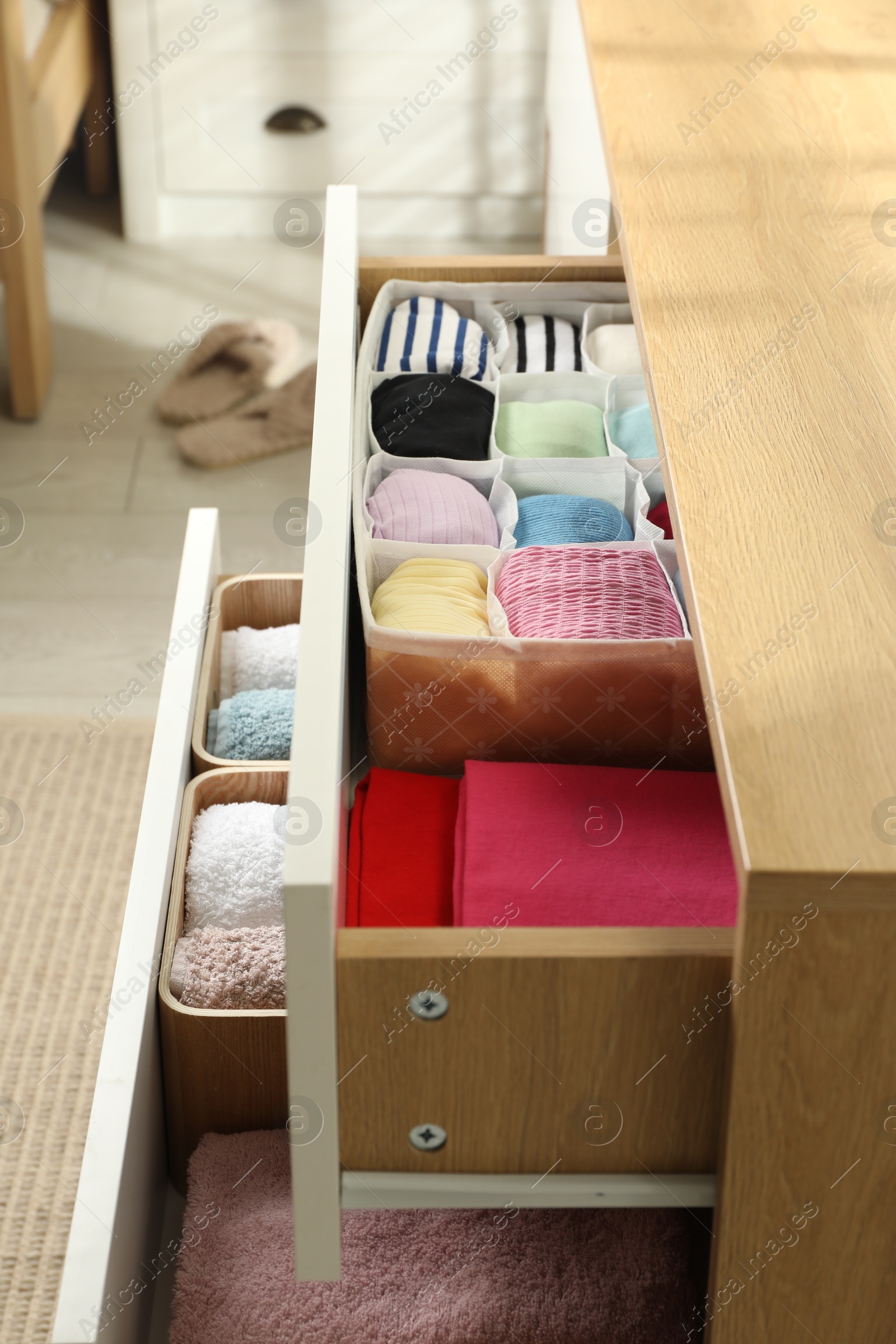 Photo of Chest of drawers with different folded clothes indoors, closeup