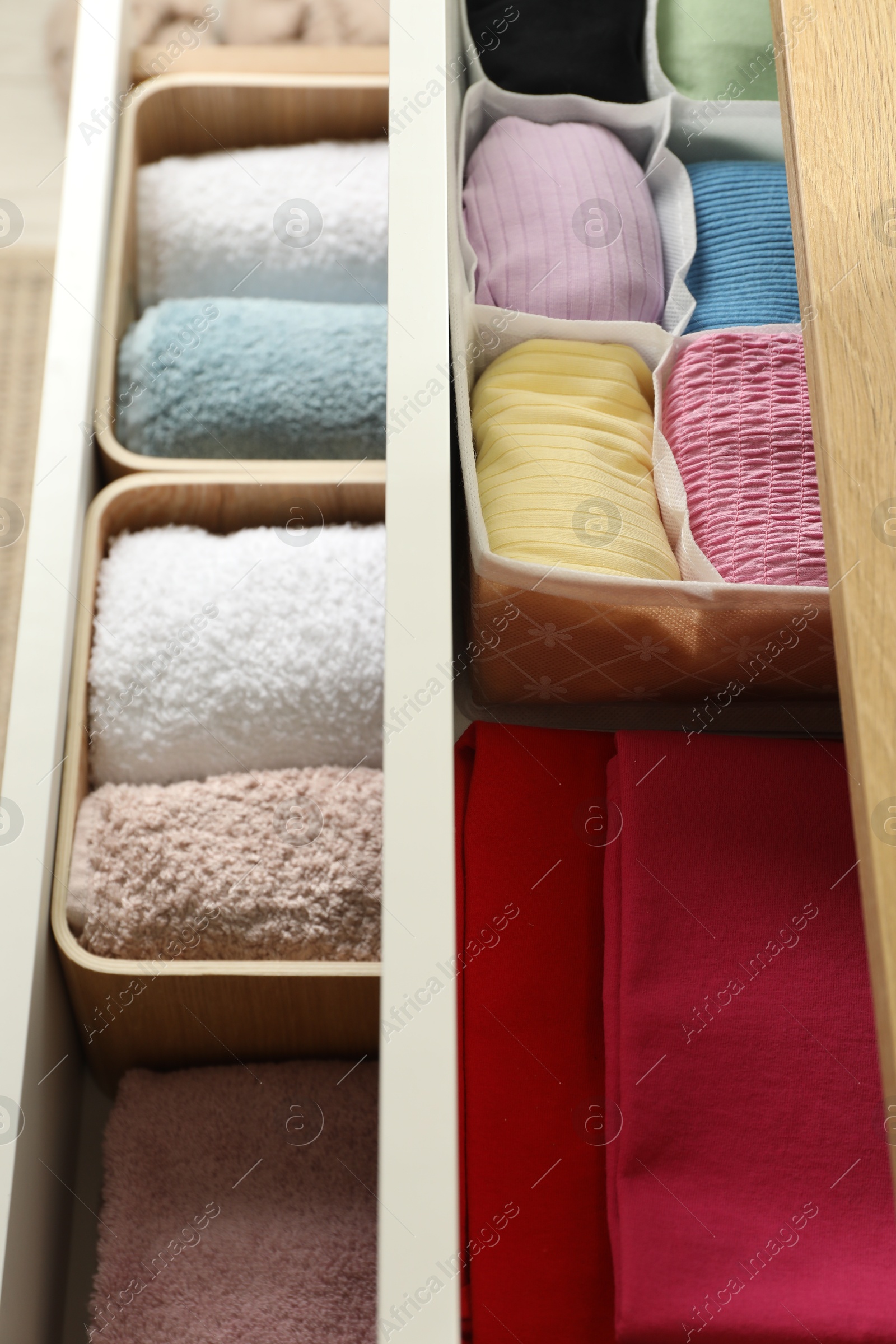 Photo of Chest of drawers with different folded clothes, closeup