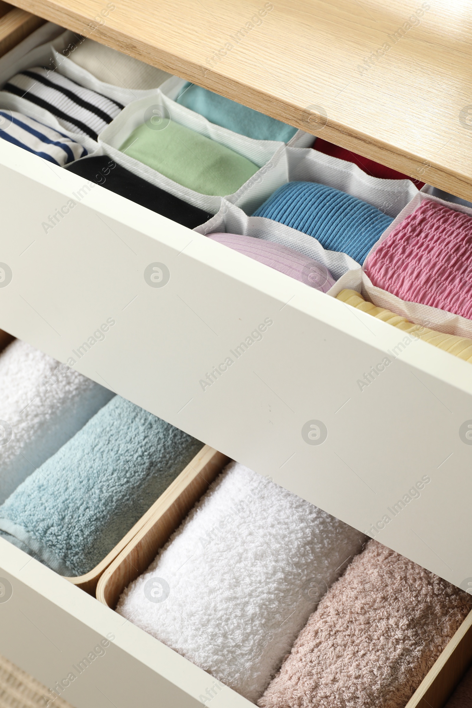 Photo of Chest of drawers with different folded clothes, closeup