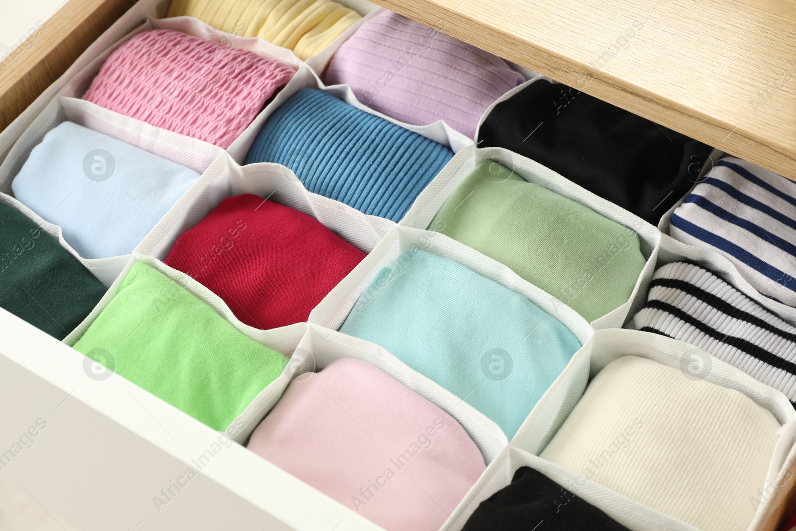 Photo of Chest of drawers with different folded clothes, closeup