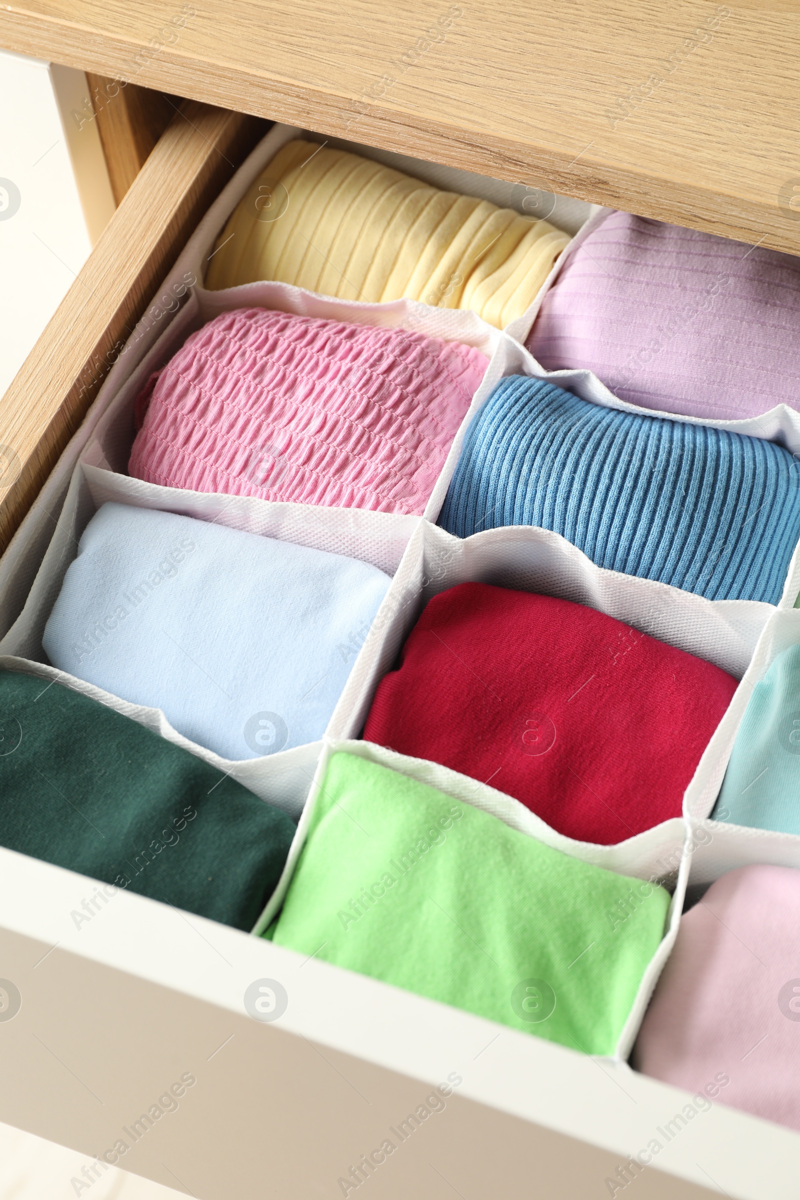 Photo of Chest of drawers with different folded clothes, closeup