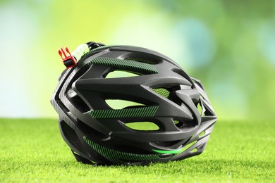 Photo of Stylish protective helmet on green grass against blurred background