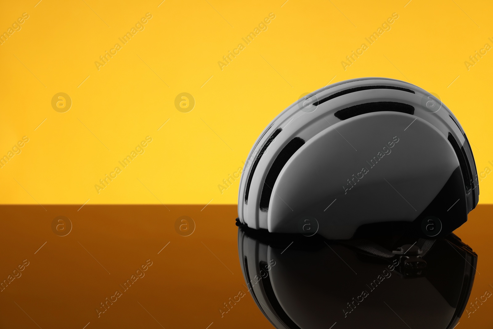 Photo of White protective helmet on mirror surface against orange background. Space for text