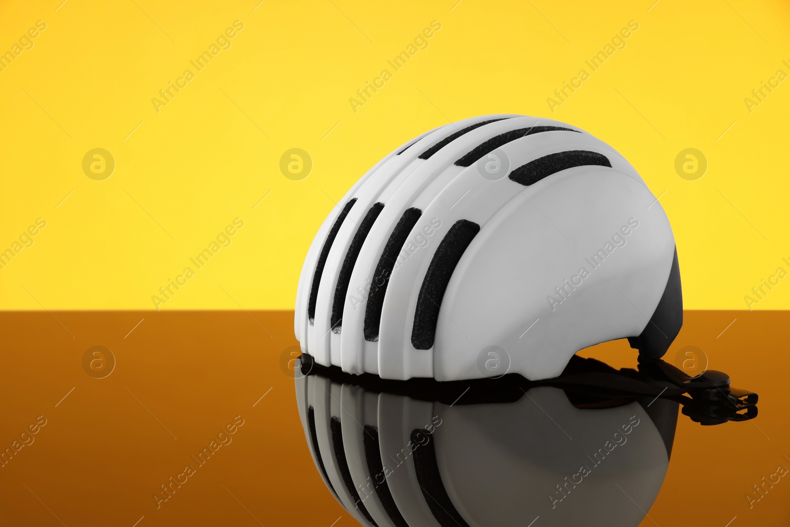 Photo of White protective helmet on mirror surface against yellow background. Space for text