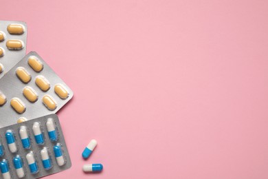 Photo of Different antibiotic pills in blisters on pink background, flat lay. Space for text