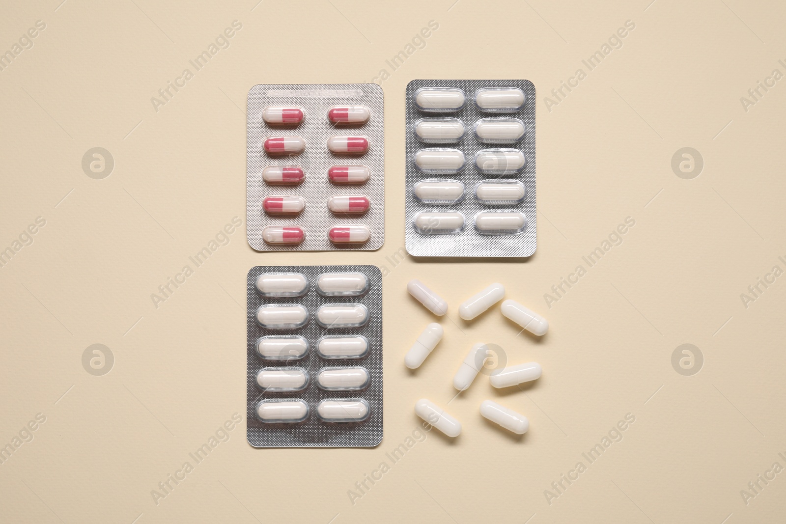 Photo of Different antibiotic pills in blisters on beige background, flat lay