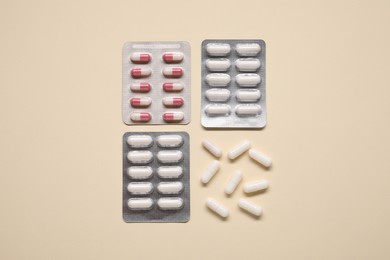 Different antibiotic pills in blisters on beige background, flat lay