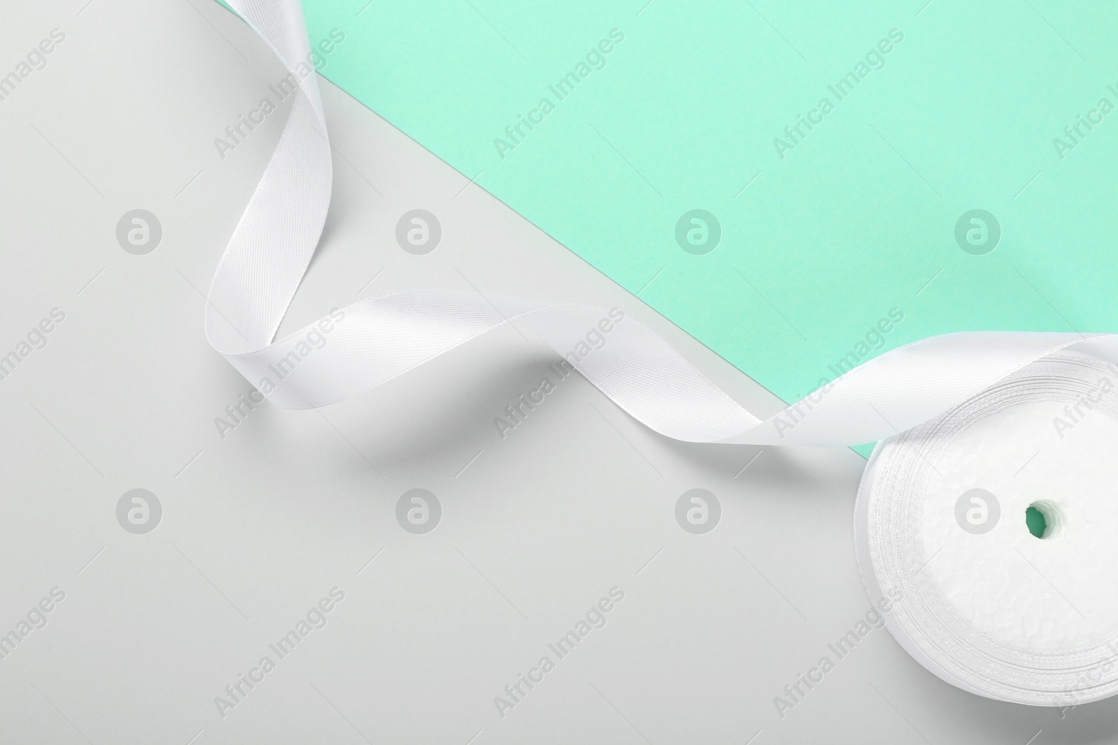 Photo of Beautiful white ribbon reel on color background, top view. Space for text