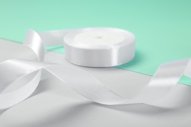 Photo of Beautiful white ribbon reel on color background, closeup