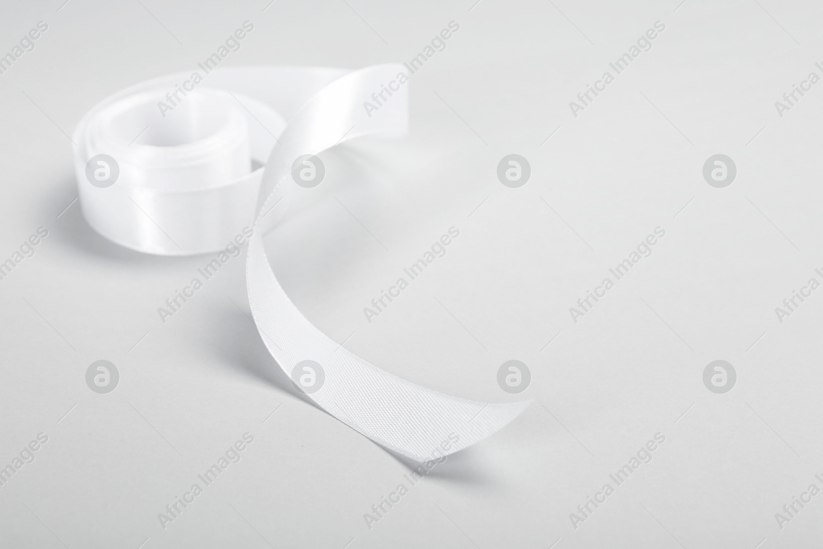 Photo of Beautiful white ribbon reel on light background. Space for text