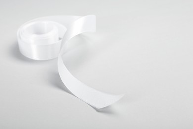 Beautiful white ribbon reel on light background. Space for text