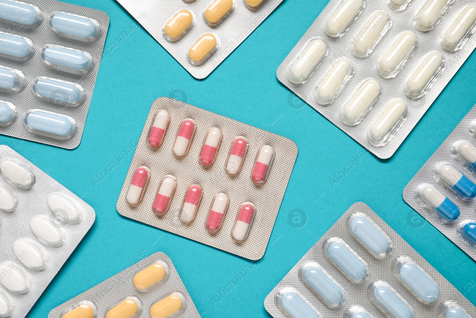 Photo of Antibiotic pills in blisters on light blue background, flat lay