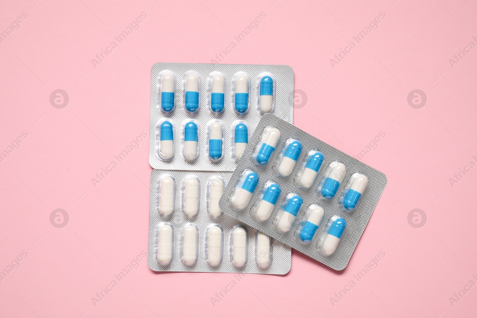 Photo of Antibiotic pills in blisters on pink background, top view