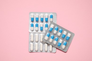 Photo of Antibiotic pills in blisters on pink background, top view