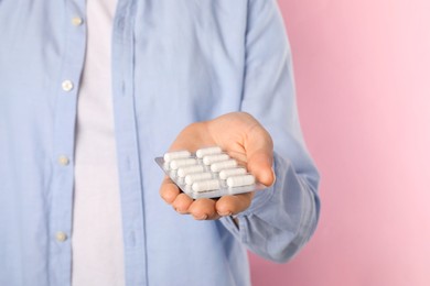 Woman holding blister with antibiotic pills on pink background, closeup