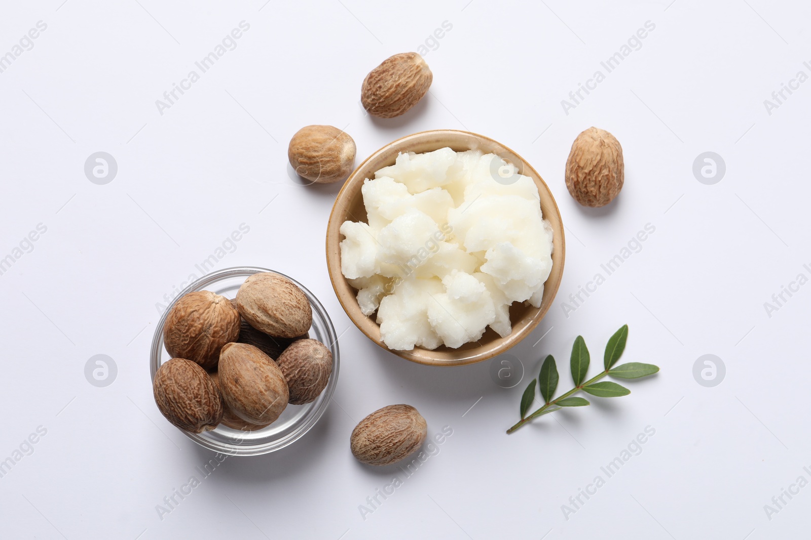 Photo of Shea butter in bowl and nuts on white background, flat lay