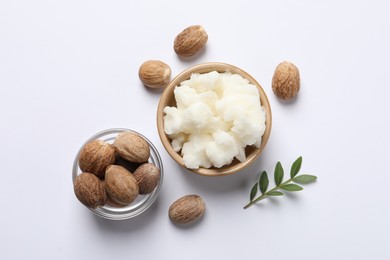 Shea butter in bowl and nuts on white background, flat lay