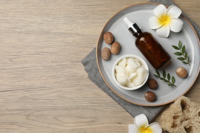 Shea butter, bottle, flowers and nuts on wooden table, top view. Space for text