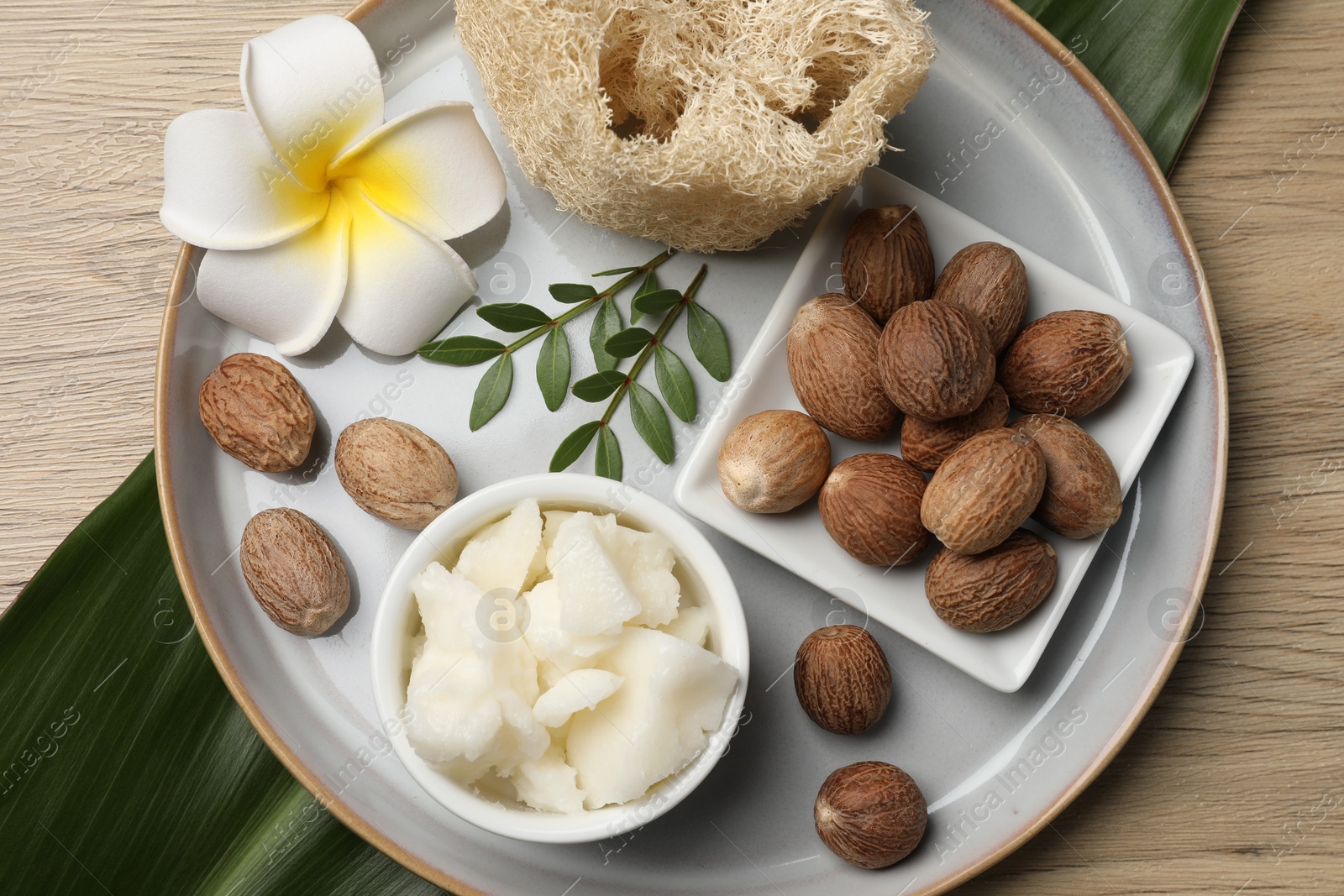 Photo of Shea butter, sponge flower and nuts on wooden table, top view