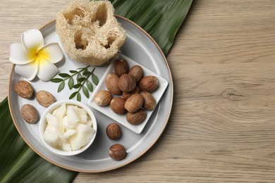 Photo of Shea butter, sponge flower and nuts on wooden table, top view. Space for text