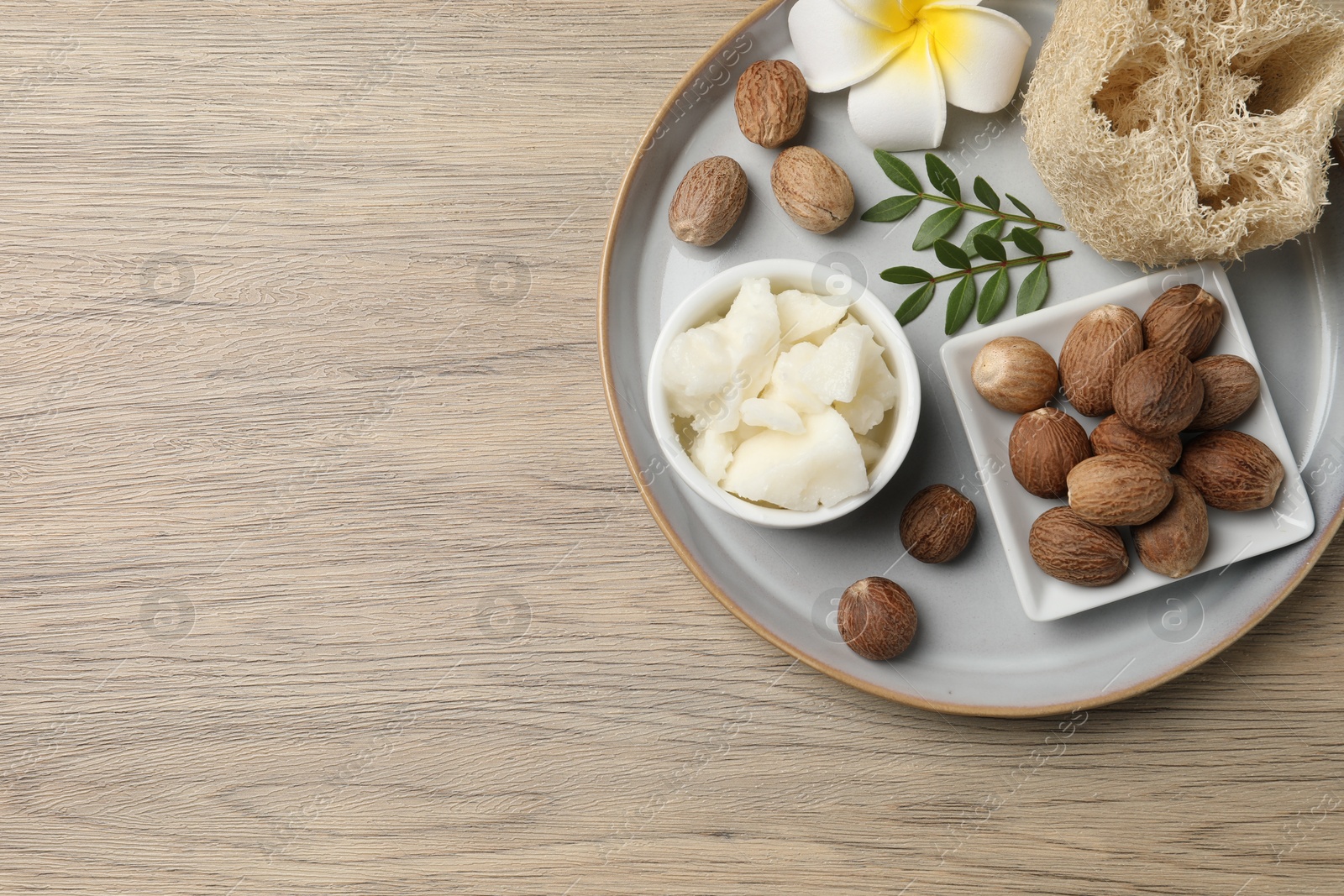 Photo of Shea butter, sponge flower and nuts on wooden table, top view. Space for text