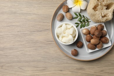 Shea butter, sponge flower and nuts on wooden table, top view. Space for text