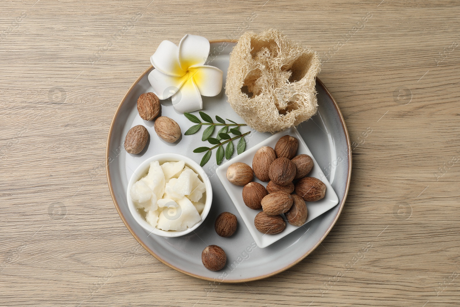 Photo of Shea butter, sponge flower and nuts on wooden table, top view