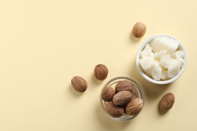 Shea butter in bowl and nuts on beige background, flat lay. Space for text