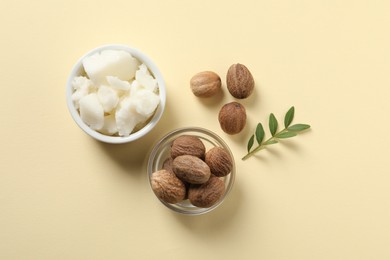 Photo of Shea butter in bowl and nuts on beige background, flat lay