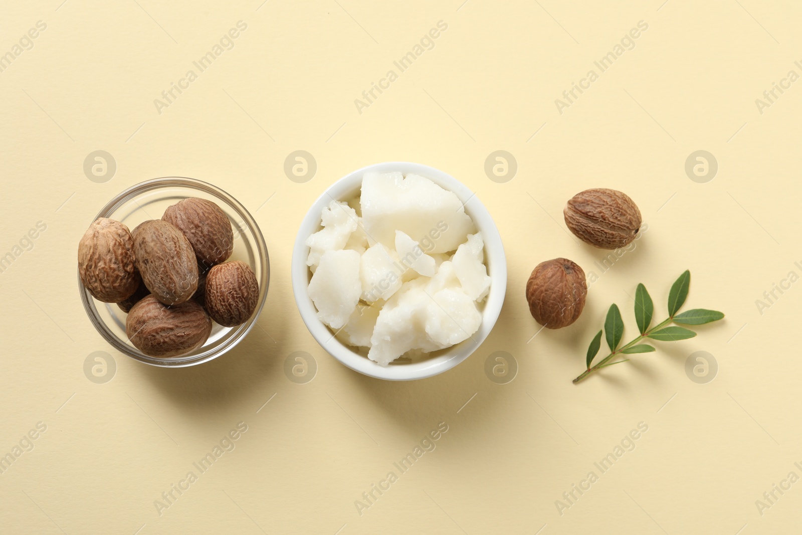 Photo of Shea butter in bowl and nuts on beige background, flat lay