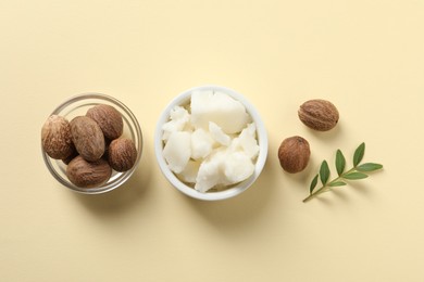 Photo of Shea butter in bowl and nuts on beige background, flat lay