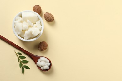 Shea butter in bowl, spoon and nuts on beige background, flat lay. Space for text