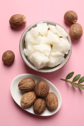 Shea butter in bowl and nuts on pink background, flat lay