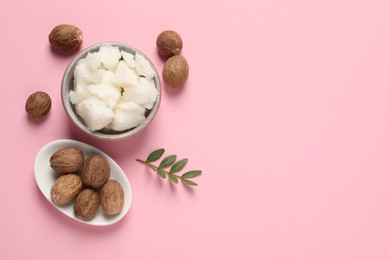 Shea butter in bowl and nuts on pink background, flat lay. Space for text