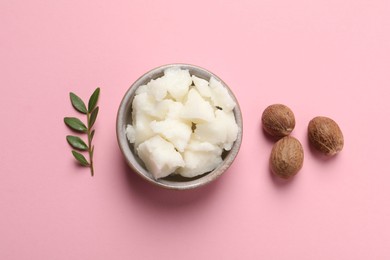 Shea butter in bowl and nuts on pink background, flat lay