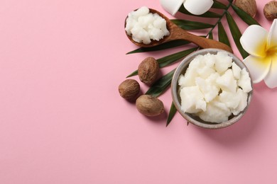 Photo of Shea butter in bowl, flower and nuts on pink background, flat lay. Space for text