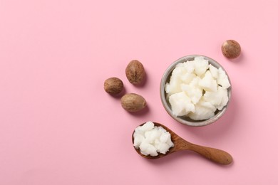 Shea butter in bowl, spoon and nuts on pink background, flat lay. Space for text