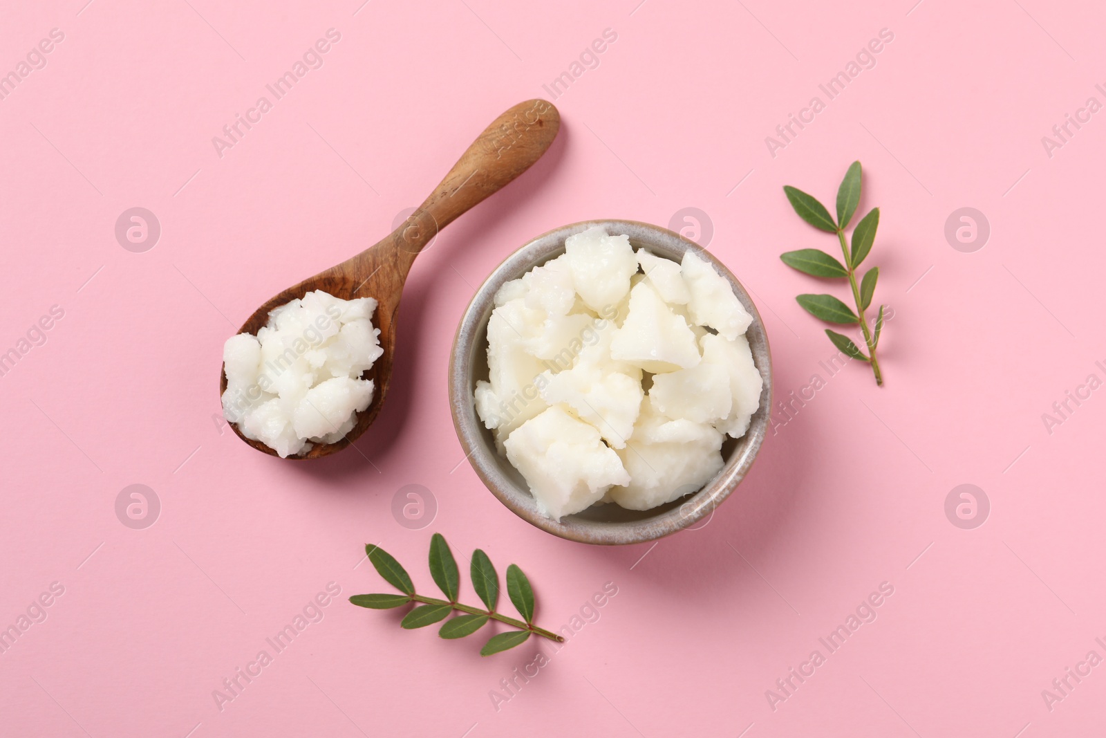 Photo of Shea butter in bowl and spoon on pink background, flat lay