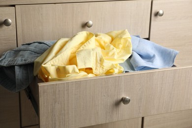 Photo of Cluttered chest of drawers, closeup. Clothes in mess