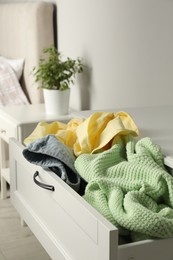 Cluttered chest of drawers indoors, closeup. Clothes in mess