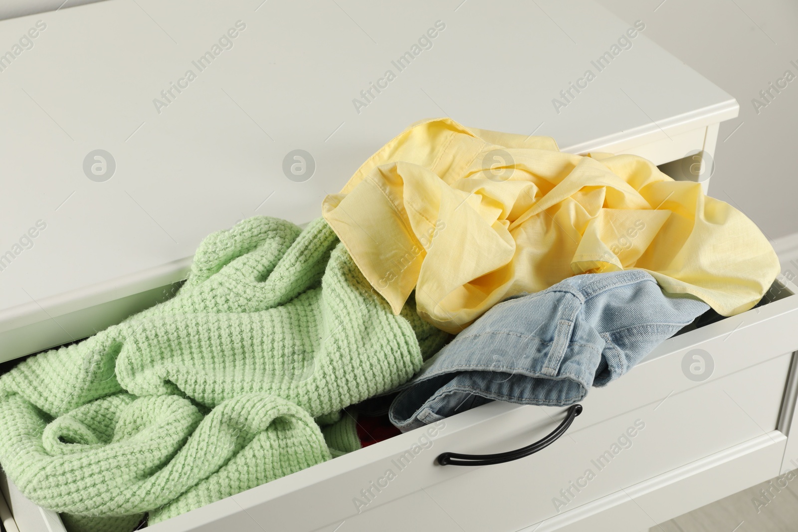 Photo of Cluttered chest of drawers, closeup. Clothes in mess