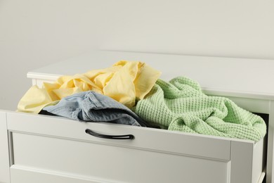 Photo of Cluttered chest of drawers indoors, closeup. Clothes in mess