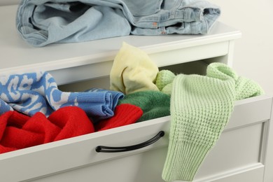 Photo of Cluttered chest of drawers indoors, closeup. Clothes in mess