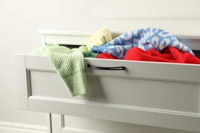 Photo of Cluttered chest of drawers indoors, closeup. Clothes in mess