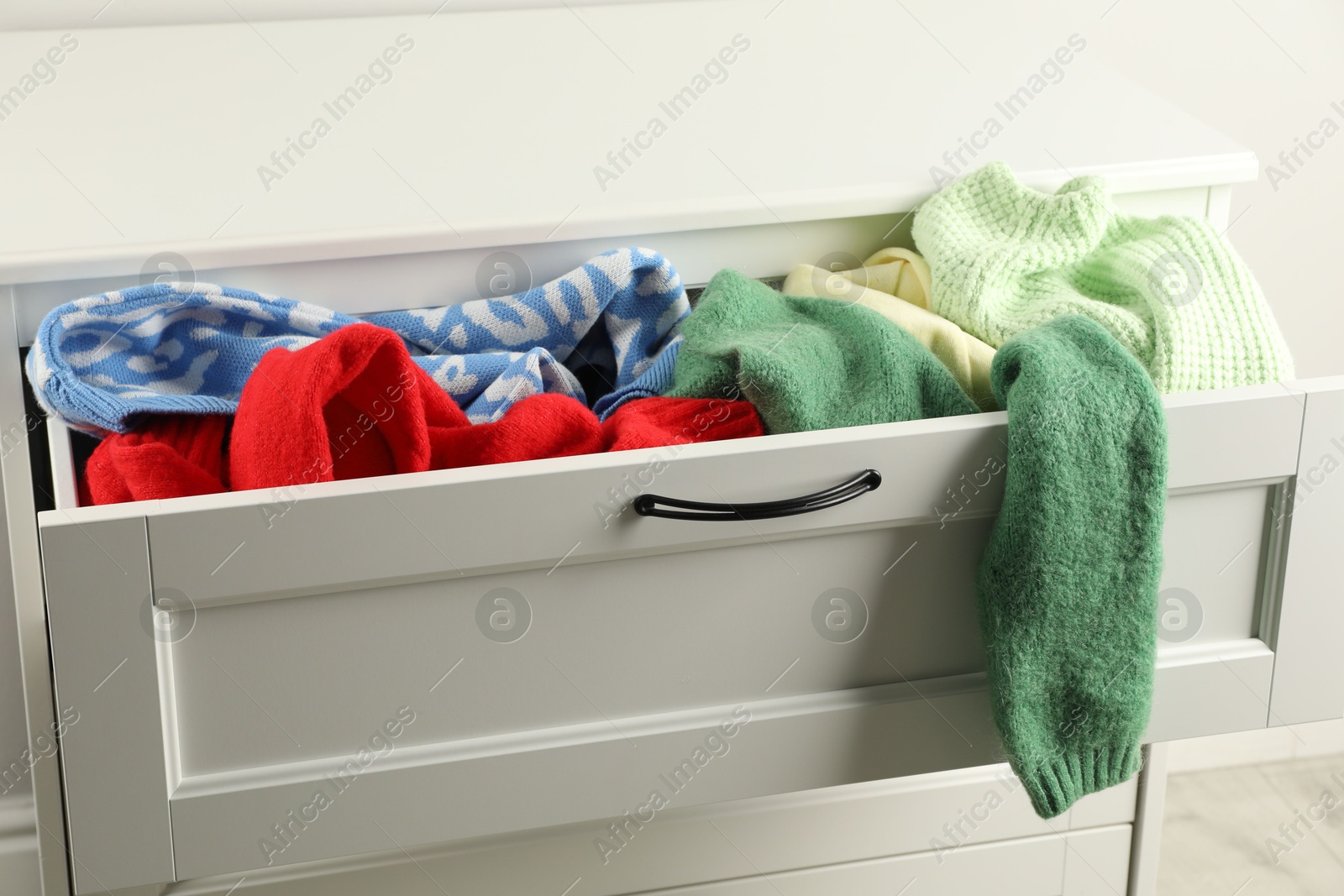 Photo of Cluttered chest of drawers indoors, closeup. Clothes in mess