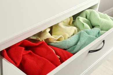 Cluttered chest of drawers indoors, closeup. Clothes in mess